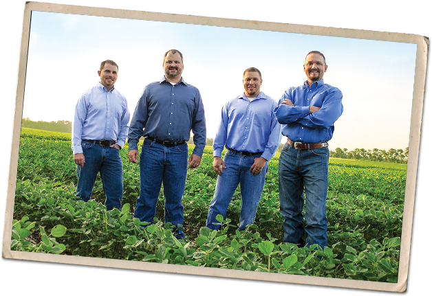 Four men standing in a field.