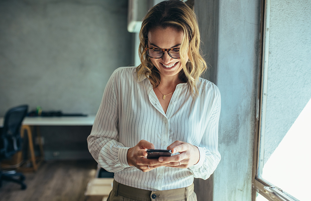 A business woman smiles while looking at her mobile phone